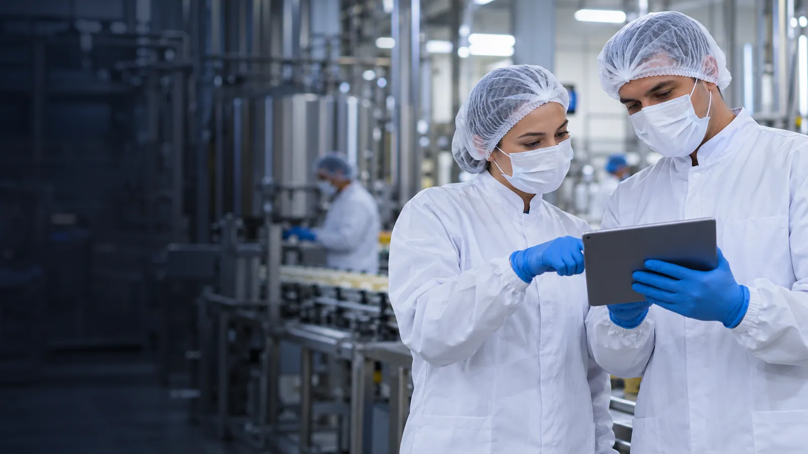 Equipe de qualidade analisando indicadores em um tablet na área de produção